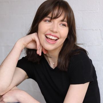 Young woman smiling with hand on chin.