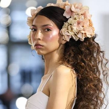 Woman with flowers in her hair and glowing makeup.