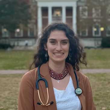 Young woman with stethoscope outside a university building.