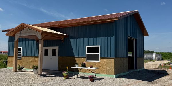 Blue and wooden barn with plants and table outside.