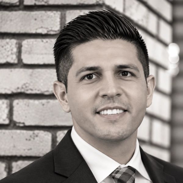 Professional headshot of a man in a suit smiling.