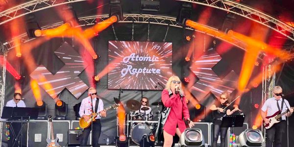 Band Atomic Rapture performing live on stage with vibrant lights.