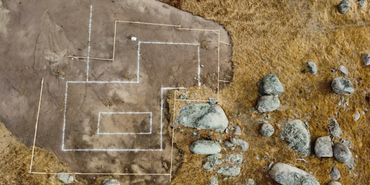 An aerial view of a marked archaeological site with rocks and soil.