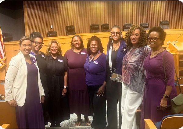 Group of women posing in formal attire in a meeting room.