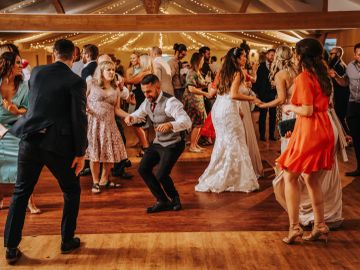 Guests dancing joyfully at a wedding reception with the bride in white.