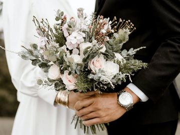 Bride and groom holding a bouquet of flowers together.