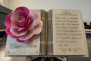 Decorative book-shaped plaque with a pink paper flower and a heartfelt message to Mom.