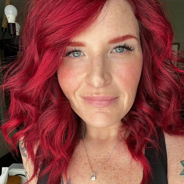 Close-up of a woman with vibrant red hair and blue eyes.