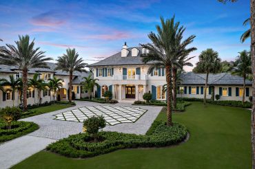 Luxury mansion with palm trees at dusk.