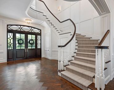 Elegant foyer with curved staircase and double door entrance.