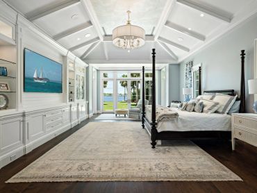 Elegant coastal-themed bedroom with large rug and four-poster bed.