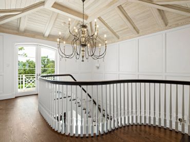 Elegant staircase with wooden floors and chandelier.
