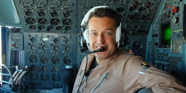 Pilot smiling inside aircraft cockpit.