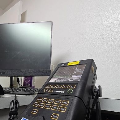 Olympus diagnostic device next to a computer monitor on a desk.