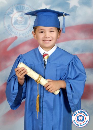 Young boy in blue graduation gown holding diploma, smiling.