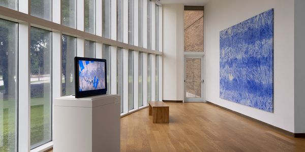 Modern art gallery with a TV display and blue abstract painting on the wall.