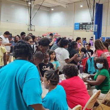 Crowd and volunteers at a community health event in a gym.