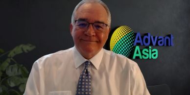 Smiling man in glasses and tie with Advant Asia logo background.
