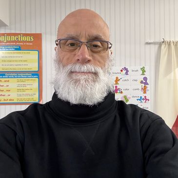 A man with glasses and a white beard wearing a black turtleneck sweater.