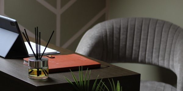 Cozy workspace with a gray chair, reed diffuser, and organized desk.