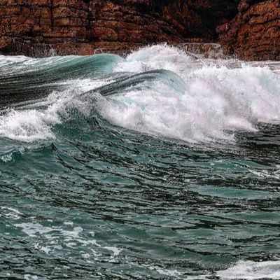 Powerful ocean waves crashing against rocky cliffs.