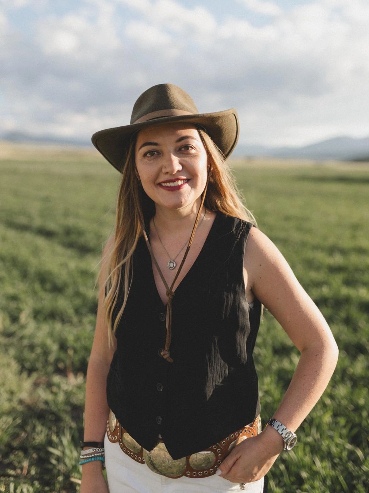 Woman in a hat smiling outdoors.