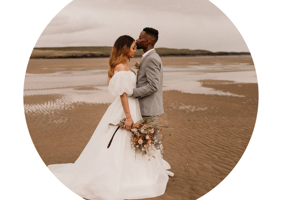 Bride and groom sharing a tender moment on a sandy beach.