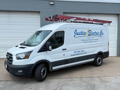A white Justice Electric Co. van parked outside a garage.