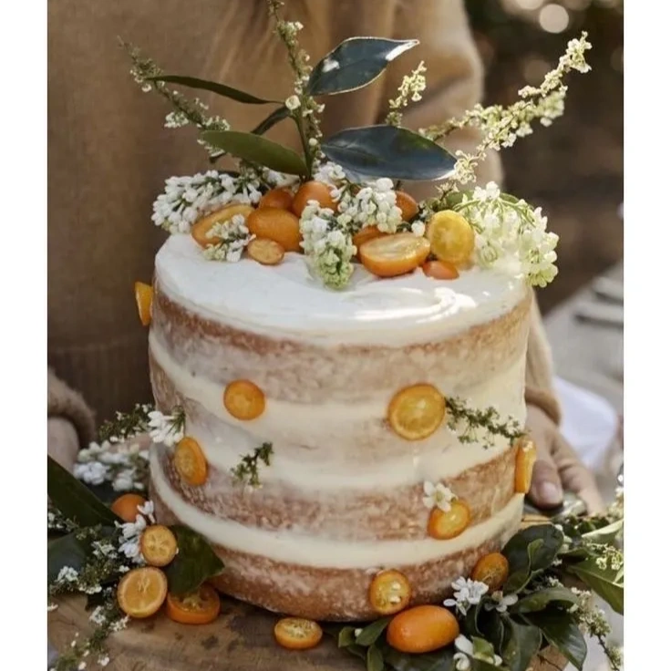 Rustic layered cake decorated with kumquats and white flowers.