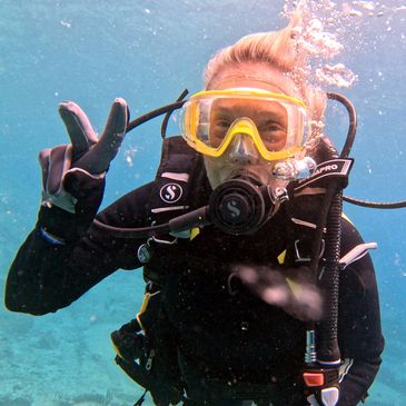 Scuba diver underwater making a peace sign gesture.