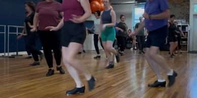 Group of people tap dancing indoors.