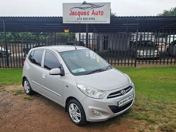 Silver Hyundai hatchback parked on grass at Jacques Auto dealership.
