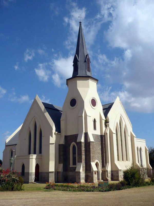 A Gothic-style church with a tall spire under a blue sky.