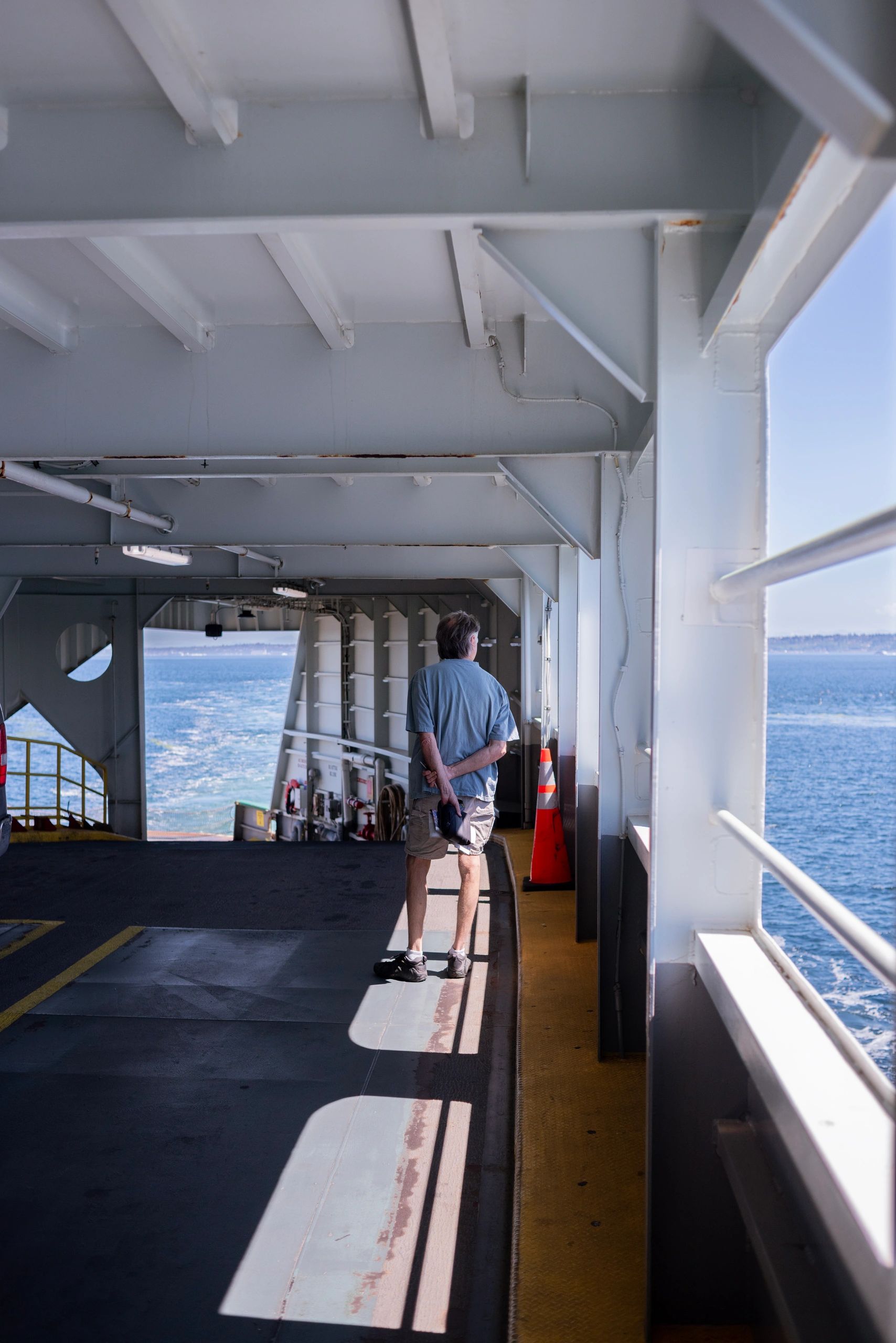 Man standing on a ferry looking at the ocean.