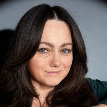 Close-up portrait of a woman with dark hair and light eyes.