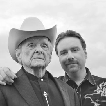 An older man in a cowboy hat with a younger man beside him.