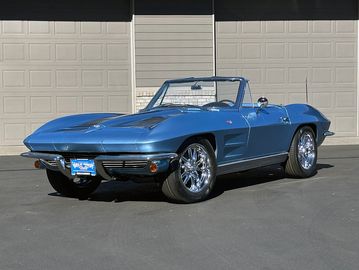 Blue vintage convertible sports car parked outdoors.
