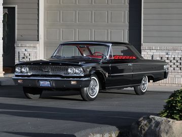 Black vintage classic car parked in front of a garage.