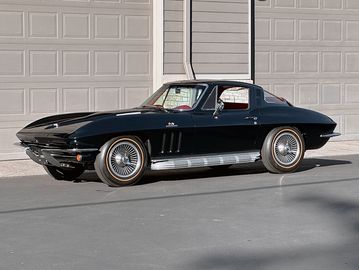 Classic black sports car parked outside a garage.
