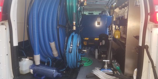 Inside view of a utility van with cleaning equipment and hoses.