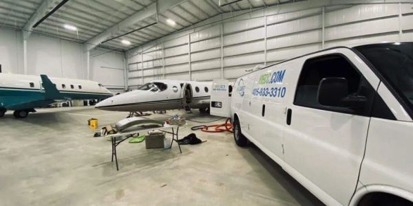 Private jets and a service van in a hangar.