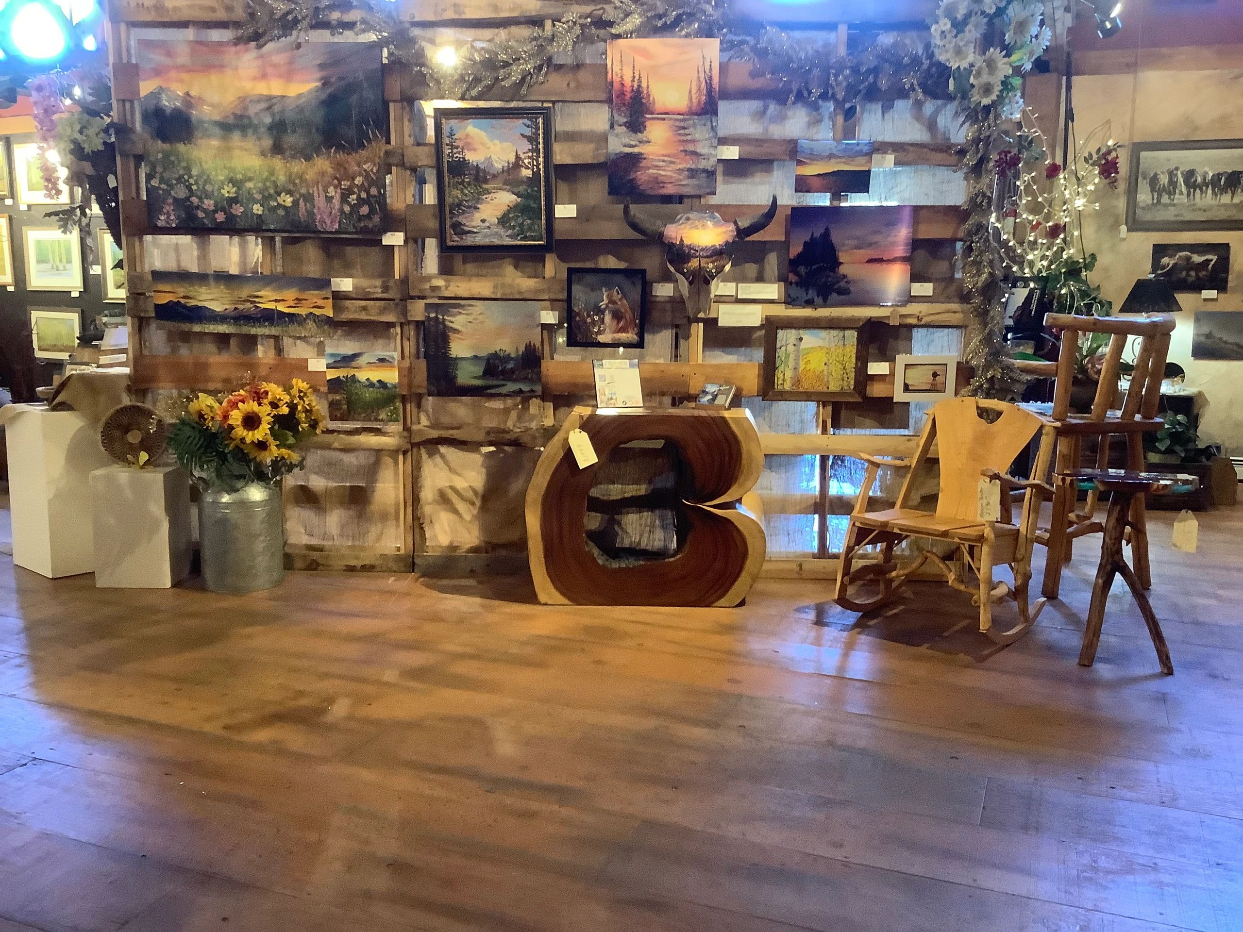 Rustic art gallery with nature paintings and wooden furniture.