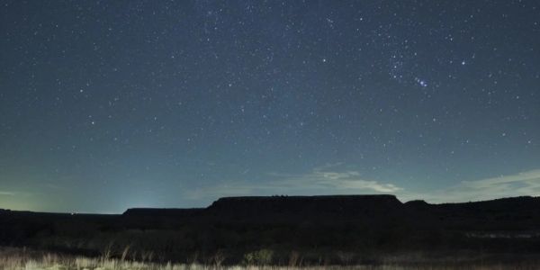 Starry night over silhouetted landscape.