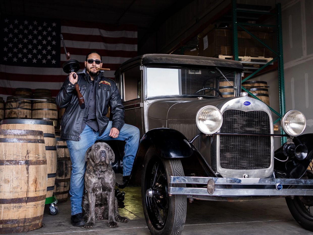 Richard Paul, the Founder of Art of the Spirits Distillery, standing next to a vintage car