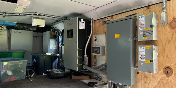Electrical control panel and equipment mounted on a wooden wall in an industrial setting.