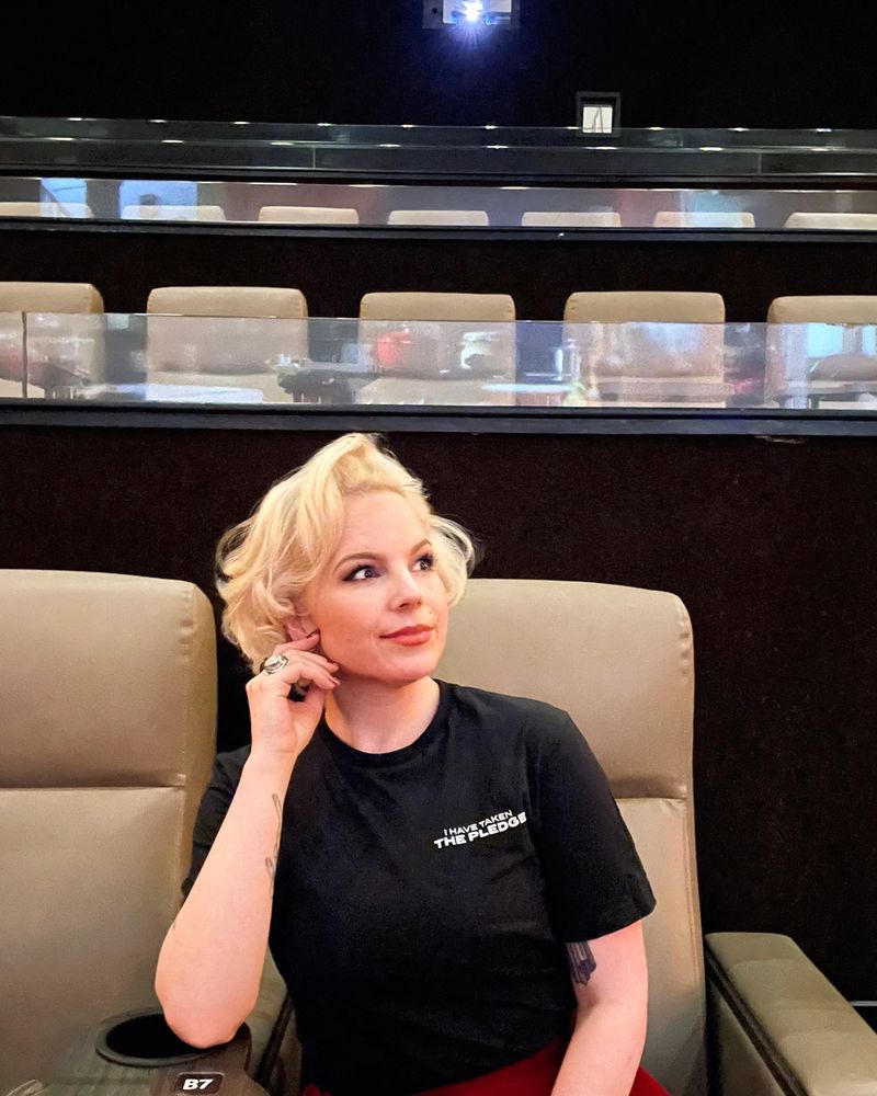 Kitty Anne sitting in a theater chair and looking thoughtfully to the side