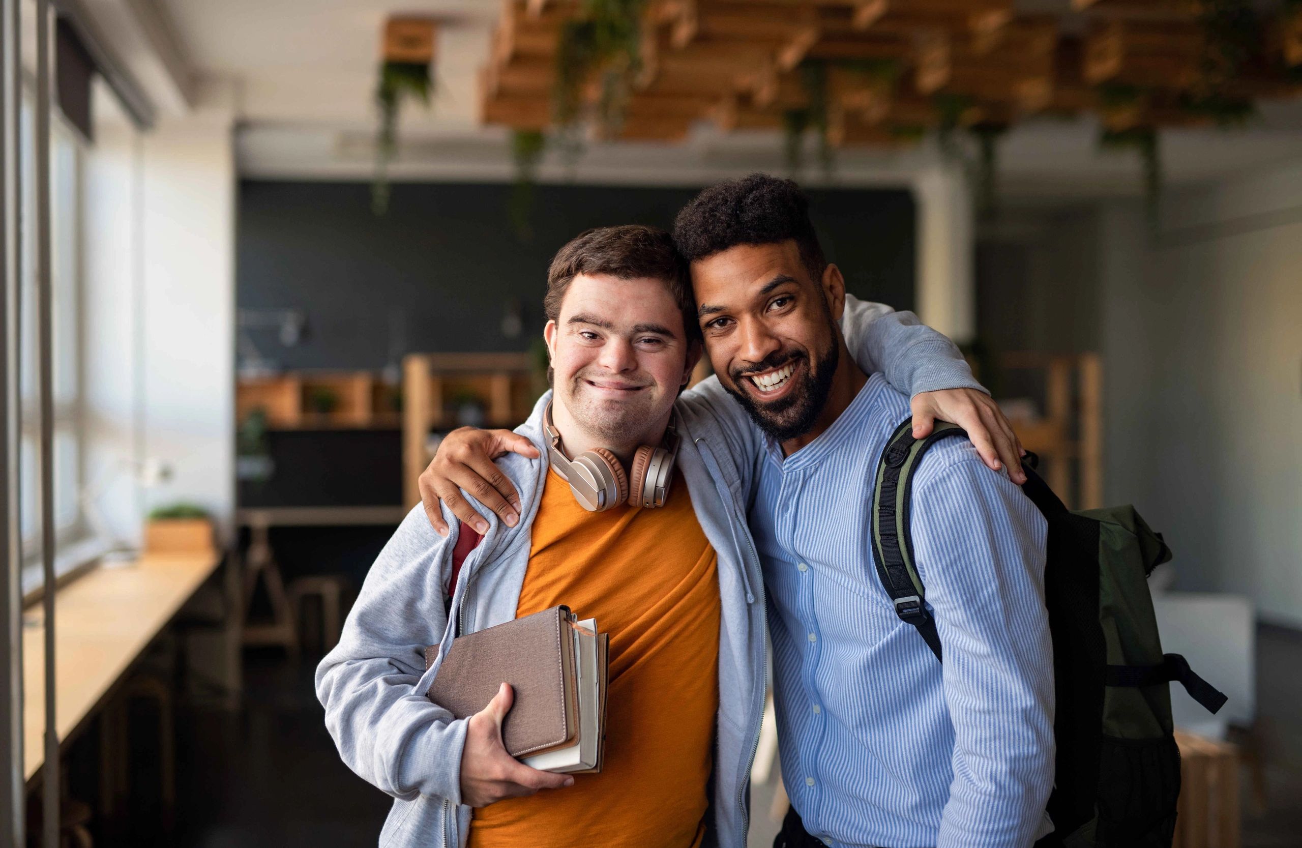 NDIS support worker smiling with a young man with Down syndrome, providing disability care.