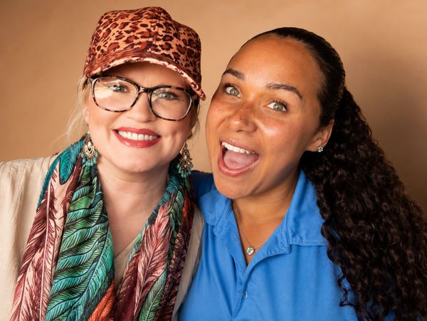 Two happy women smiling together indoors.