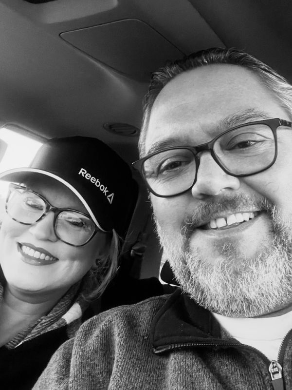 Smiling couple wearing glasses in a car.