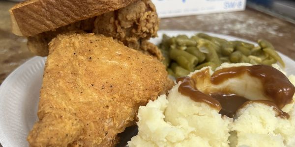 Plate of fried chicken, mashed potatoes with gravy, green beans, and bread.